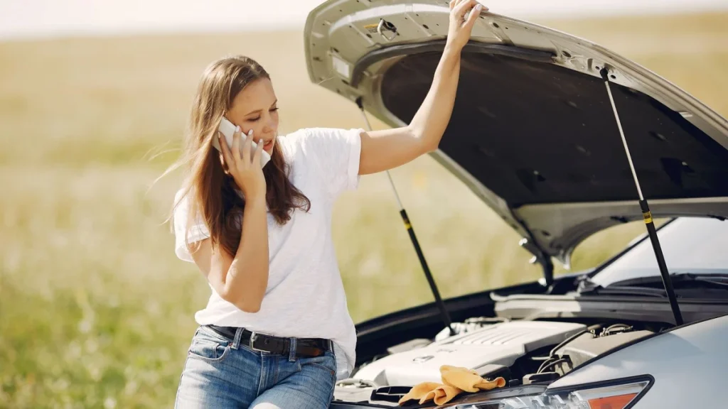 Woman on her phone beside her car, calling for help right after an accident