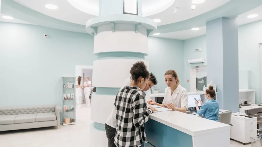 Patients checking in at a bright clinic reception for lower back pain care