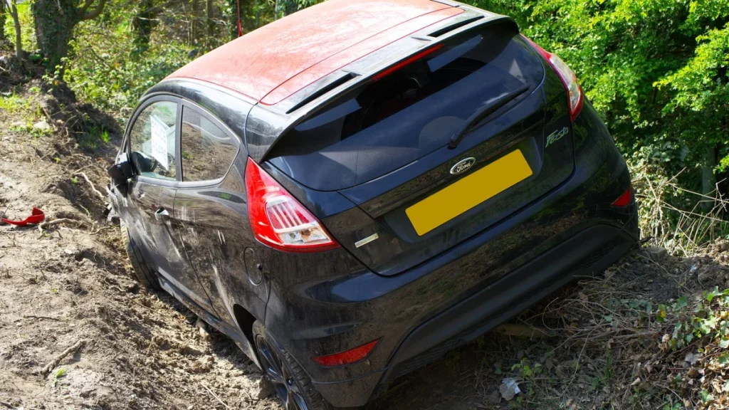 Black car crashed near trees, a reminder to seek early chiropractic care