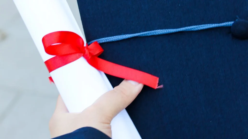 Graduate holding a diploma and cap after years of chiropractic training