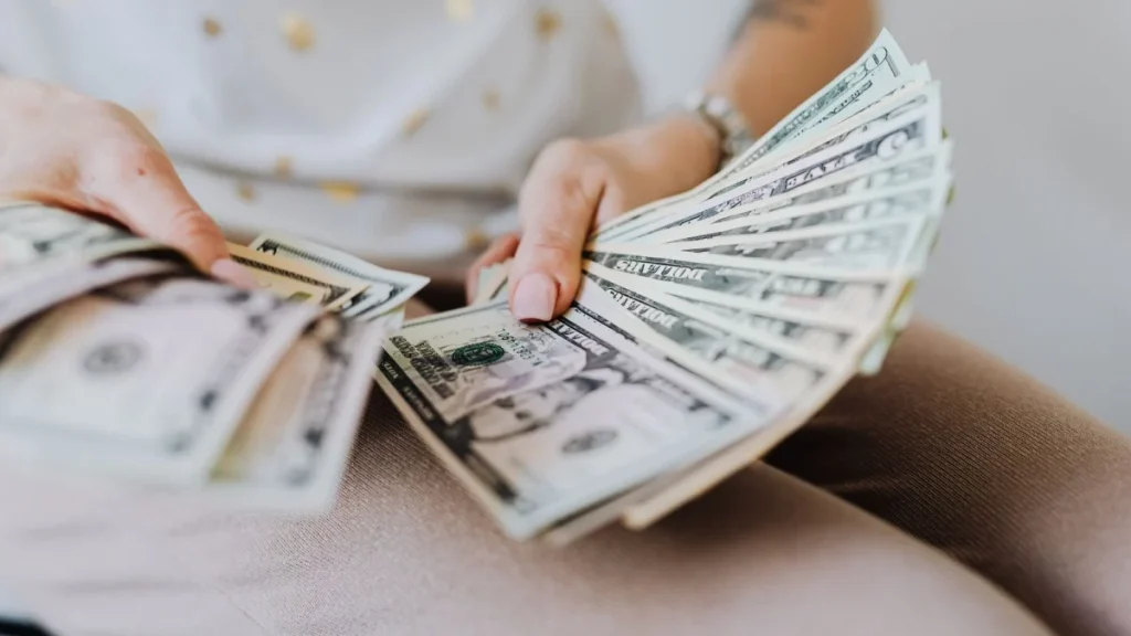 Person holding a fan of dollar bills, representing chiropractor pay in the United States