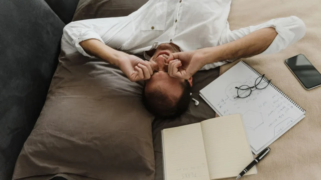 Exhausted man rubbing his eyes, showing the fatigue linked to fibromyalgia