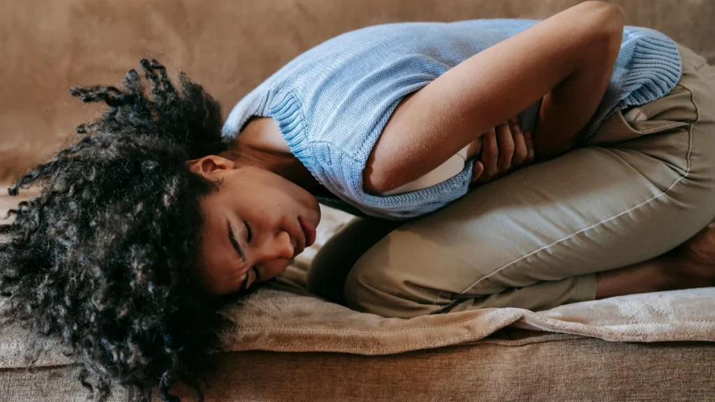 Woman doubled over holding her abdomen, as gynecological issues can cause back pain