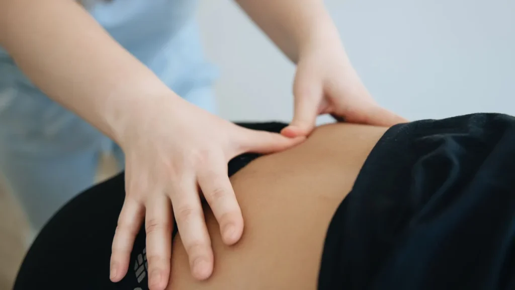 Therapist using a hands-on technique on a patient's lower back to relieve pain