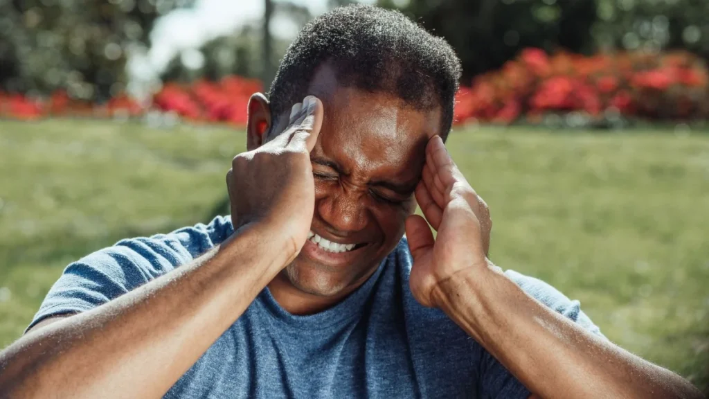 Man holding his aching head, a warning sign that neck pain needs care
