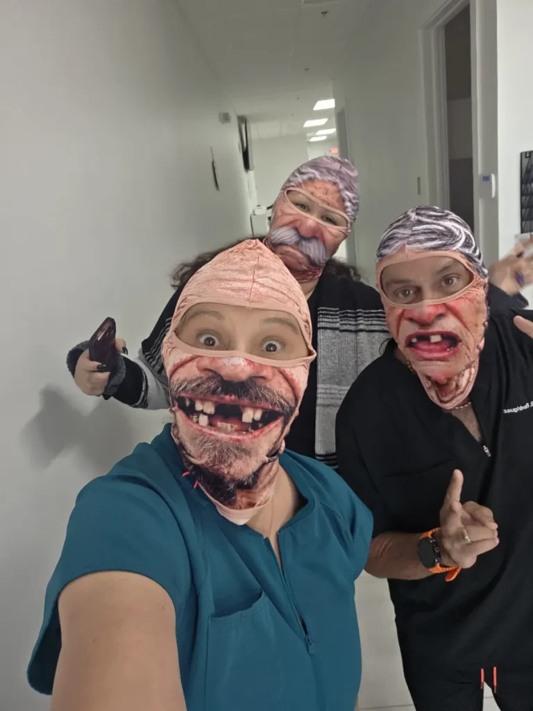 Spine and Injury Associates Kissimmee team members wearing funny masks in the clinic hallway
