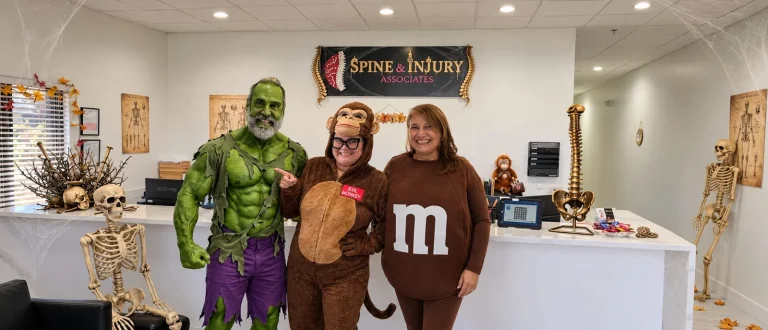 Themed Halloween 2026 photo of the Spine and Injury Associates Kissimmee team in costume at the front desk