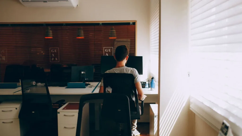 Person sitting at a computer for hours, a risk factor for chronic back pain
