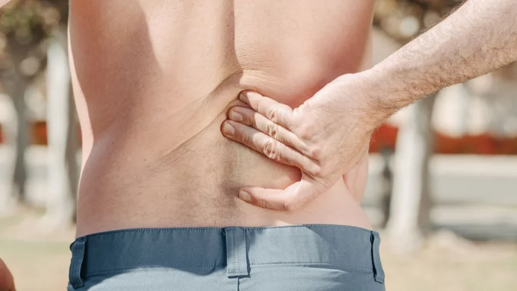 Man touching his sore back, one of the common herniated disc symptoms