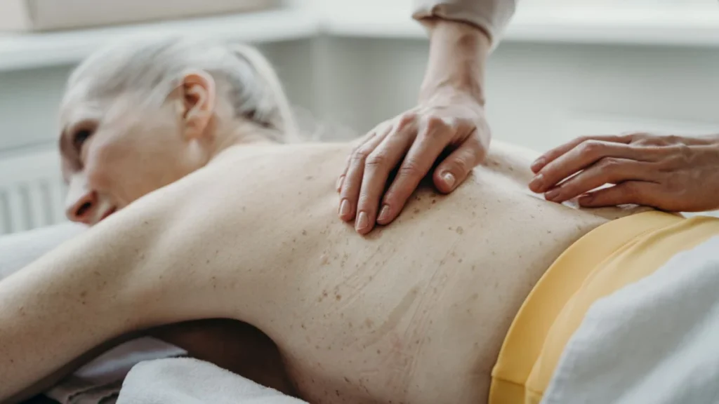 Older woman receiving a back massage to ease age-related back stiffness