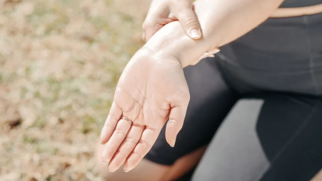 Woman gripping her wrist, a sign of overuse from repetitive movements