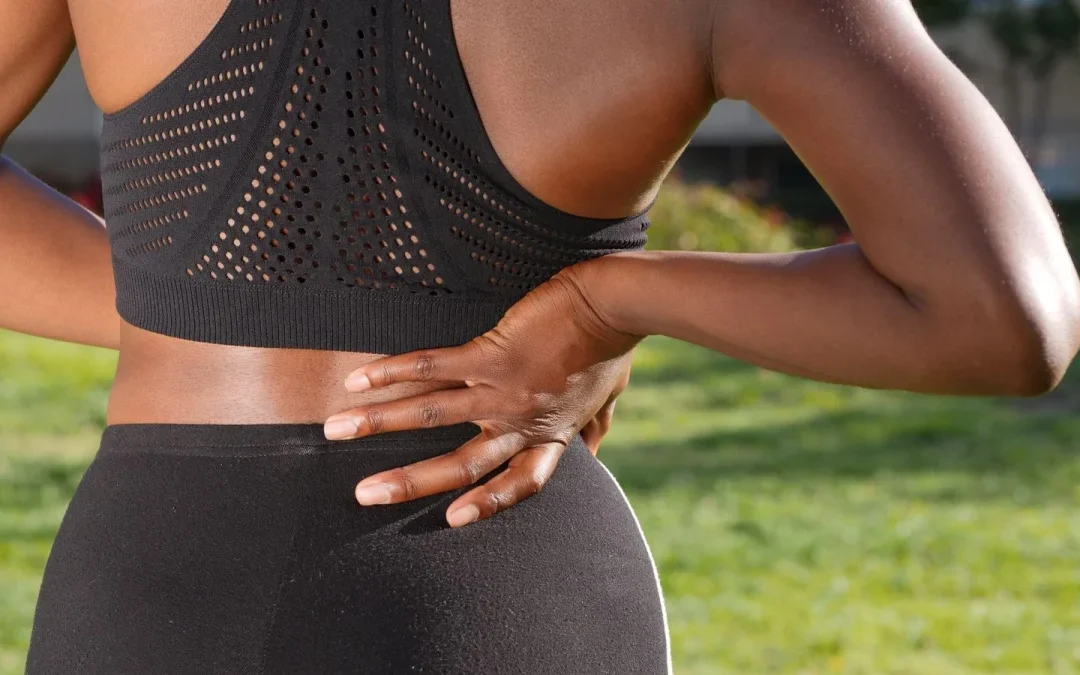 Person holding an aching lower back, illustrating common causes of back pain