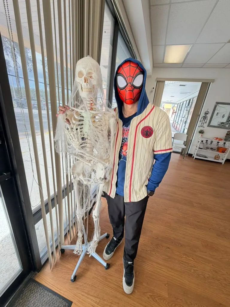 Spine and Injury Associates Plant City team member in a Spider-Man mask next to a skeleton at the clinic entrance