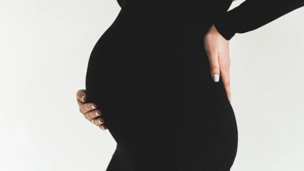 Pregnant woman holding her back and baby bump due to pregnancy back pain