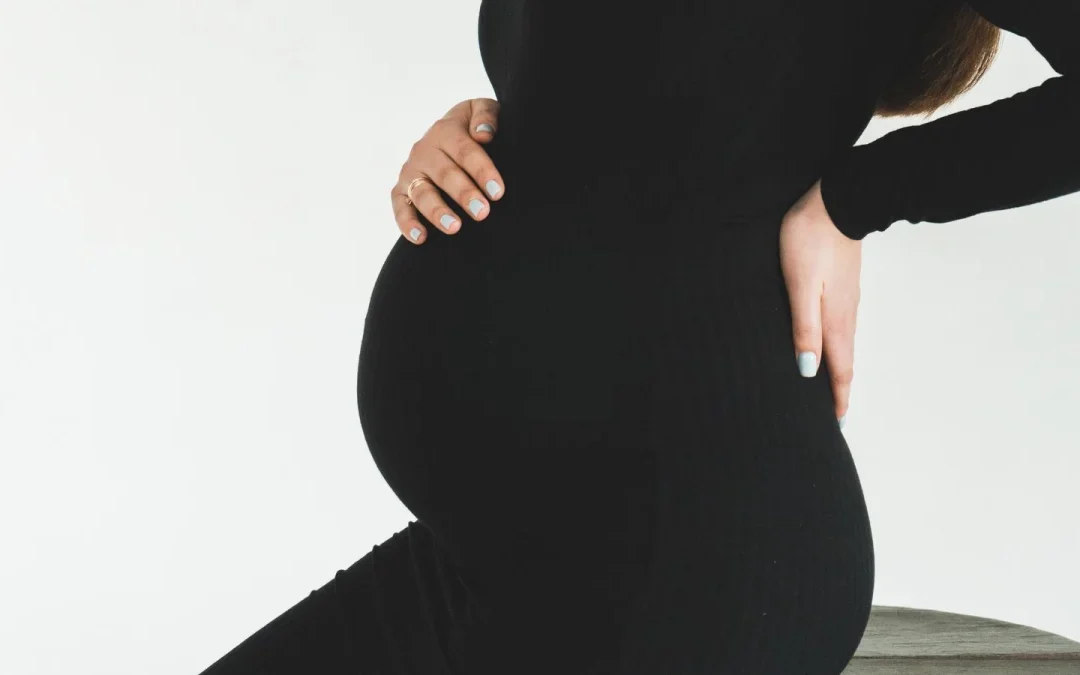 Pregnant woman supporting her belly and lower back, where chiropractic care can help