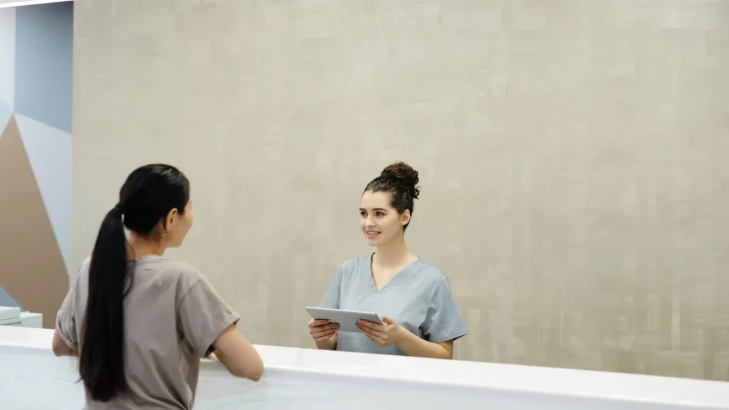 Smiling receptionist greeting a patient arriving for lower back pain care