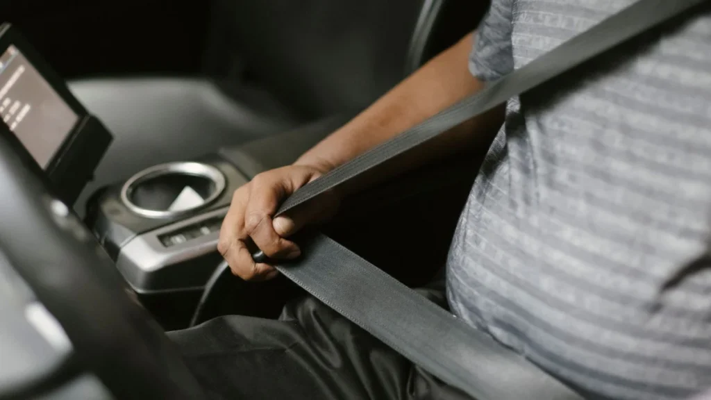 Man fastening his seat belt, a simple step that helps prevent whiplash