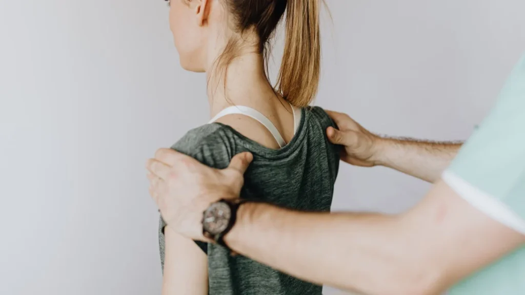 Practitioner aligning a woman's shoulders, an example of chiropractic scope of practice