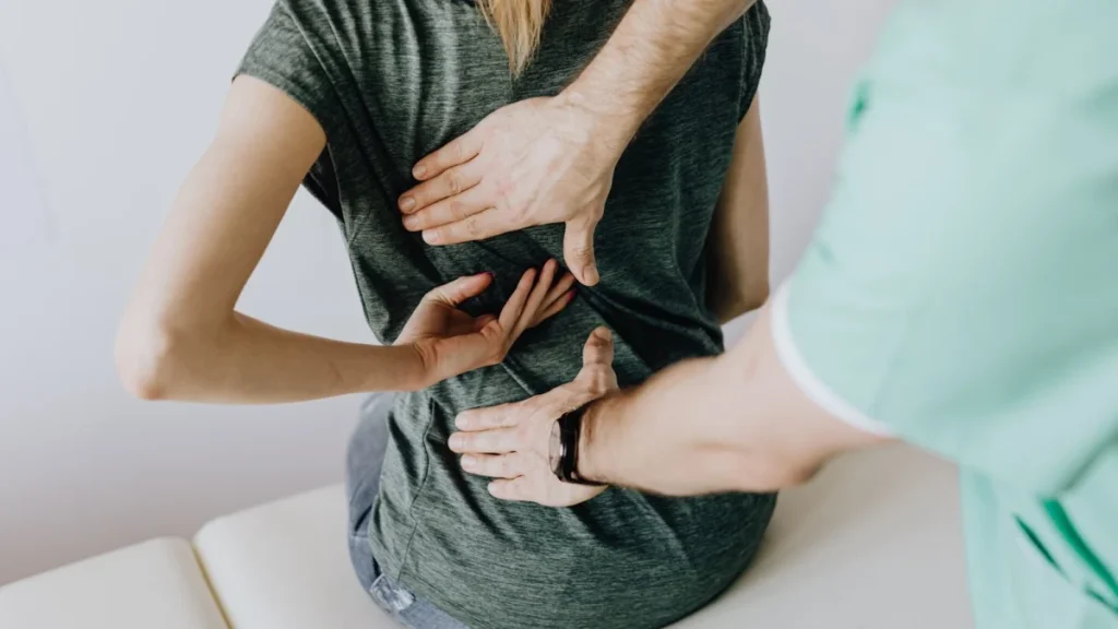 Practitioner examining a woman's back during a visit for chronic back pain