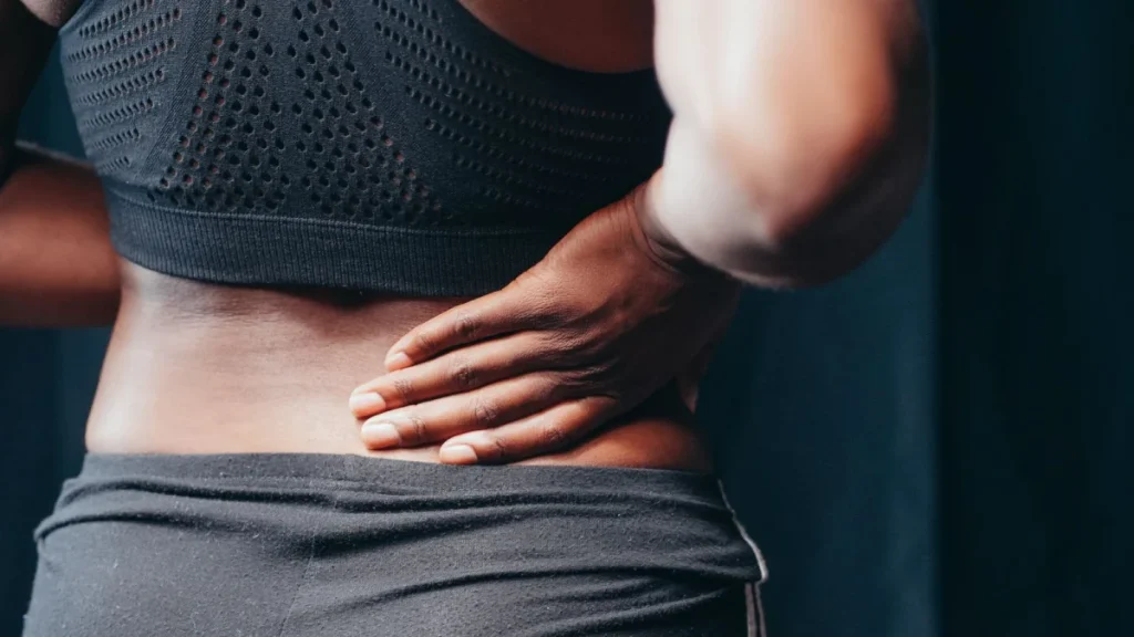Person gripping a strained lower back muscle after overexertion