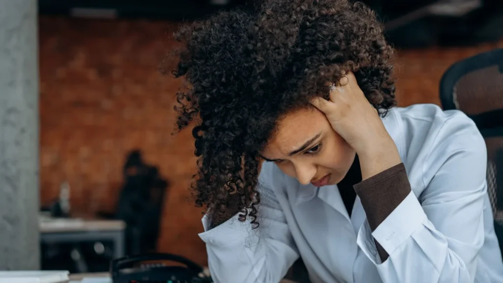Stressed woman at her desk, as emotional strain can worsen lower back pain
