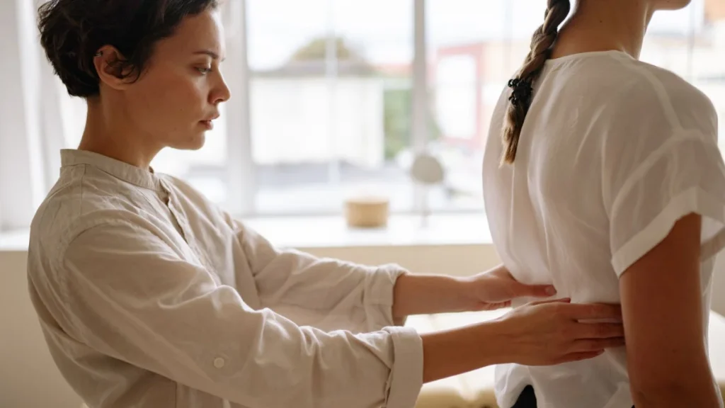 Therapist checking a woman's back to stop acute pain from becoming chronic